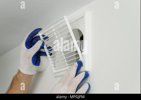 Lavoratore installa la griglia di ventilazione sul muro. Foto Stock