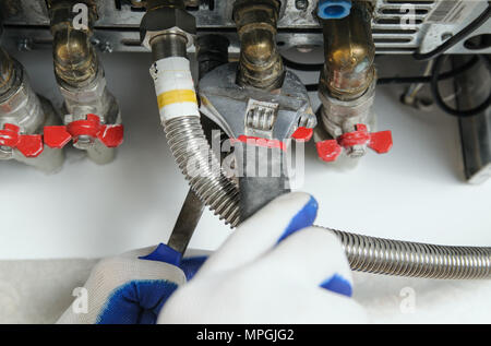 Plumber attribuisce alla canalizzazione caldaia a gas utilizzando una chiave regolabile. Foto Stock