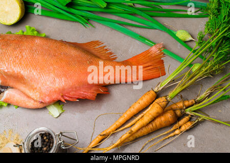 Mar Rosso pesce persico con verdure sul tavolo con giovani di carota e di spezie, calce, cipolla verde Foto Stock