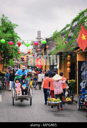 Hoi An, Vietnam - 17 Febbraio 2016: i turisti in risciò ciclo nella strada della vecchia città di Hoi An, Vietnam Foto Stock