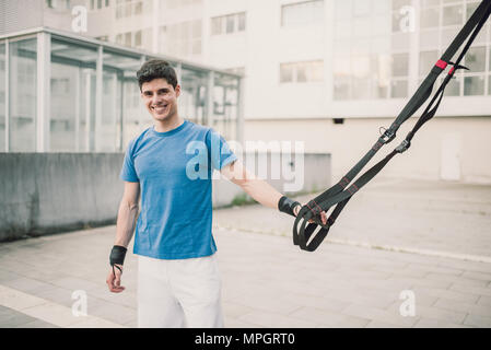 Ritratto di un maschio sportivo pronto per l'esercizio con fitness trx cinghie in strada Foto Stock