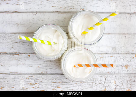 Il yogurt in tre piccoli vasetti con cannucce. vista superiore Foto Stock