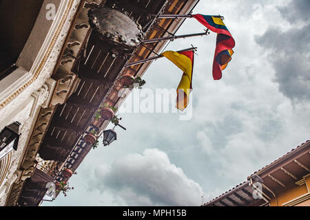 Verso l'alto vista delle bandiere ecuadoriana pendente da un edificio coloniale di Cuenca in Ecuador Foto Stock