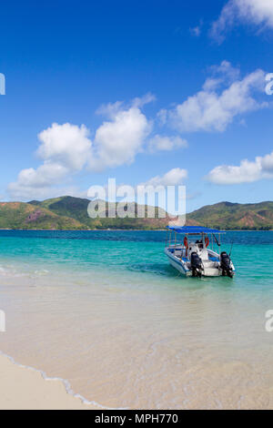 Piccola barca sulla spiaggia il Curieuse con vista a Praslin e le Seicelle. Foto Stock