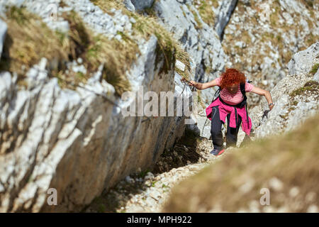 Donna free climbing su una via ferrata nelle montagne rocciose Foto Stock