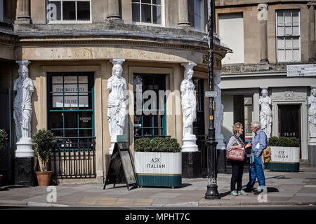 Uomo e donna che parlano in strada al di fuori di un ristorante Italiano nel quartiere di Montpellier di Cheltenham, Gloucestershire.= Foto Stock