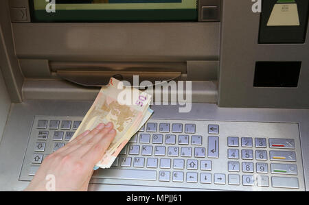 Mano che preleva il denaro delle banconote in euro da un bancomat di una banca Foto Stock