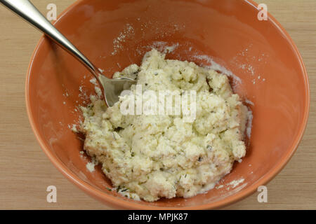 Close up di miscelazione di erbe in ricotta in Orange Bowl con cucchiaino Foto Stock