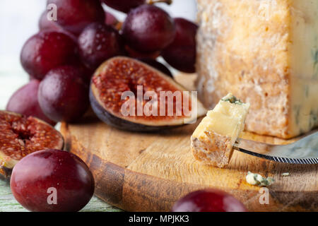 Stilton su un vassoio di formaggi con uve rosse, fig e Coltello per formaggio Foto Stock