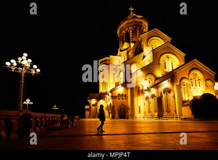 Silhouette di donna vicino la Cattedrale della Trinità o Tsminda Sameba di Chiesa di notte a Tbilisi, Georgia Foto Stock