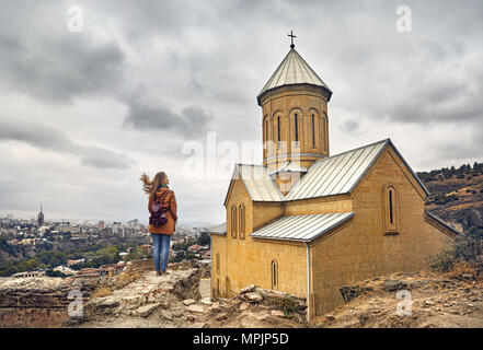 Donna turistico vicino a Cattedrale nel vecchio castello medievale di Narikala a nuvoloso cielo nuvoloso di Tbilisi, Georgia Foto Stock