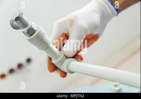 Installazione di riscaldamento domestico. Lavoratore in possesso di un tubo con una valvola. Foto Stock