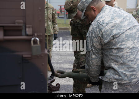 Due soldati da HHC 416th TEC sollevare e tenere una barra di traino, come un M1165 A1 tira fuori da sotto. Operazioni di recupero della formazione consente ai soldati di acquisire una comprensione di come recuperare un rotto-down, veicolo in un ambiente controllato. Operazioni di recupero è stata parte del curriculum insegnate durante HHC week-long conducente corso di formazione (U.S. Foto dell'esercito da Staff Sgt. Jason Proseus/RILASCIATO). Foto Stock