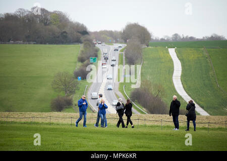 Turisti percorso a piedi a Stonehenge ascolto di audio guida anteriore del segnale di occupato a303 road Wiltshire, Inghilterra Regno Unito Foto Stock