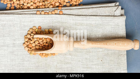 Materie lenticchie su un cucchiaio di legno su una tela di lino Foto Stock