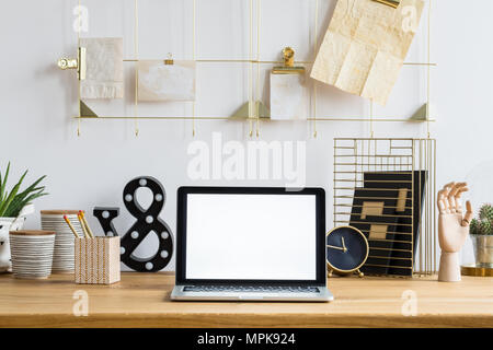 Mockup del laptop sulla scrivania in legno con orologio, piante e pentole in area di lavoro interno Foto Stock