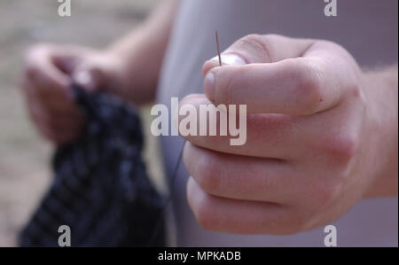 Ago con filo in la mano dell'uomo Foto Stock