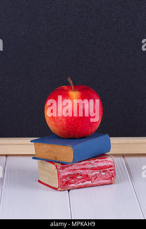 Red apple sul vecchio mini libro contro lavagna con spazio per il testo. Il concetto di scuola Foto Stock