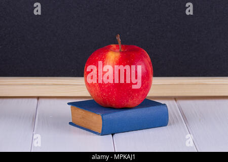 Red apple sul vecchio mini libro contro lavagna con spazio per il testo. Il concetto di scuola Foto Stock