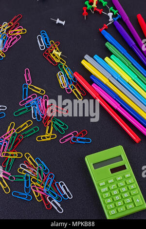 Calcolatrice, fermagli, marcatori sulla lavagna nera. La scuola e la concezione di business Foto Stock