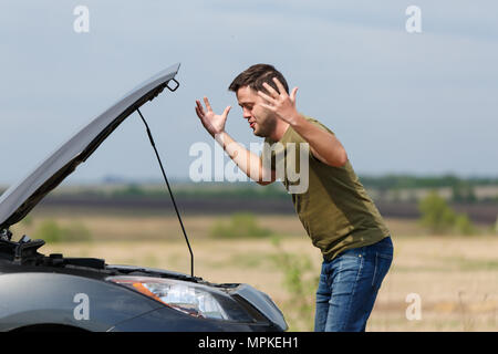 Foto di frustrato uomo accanto a Broken auto con cappa aperta Foto Stock