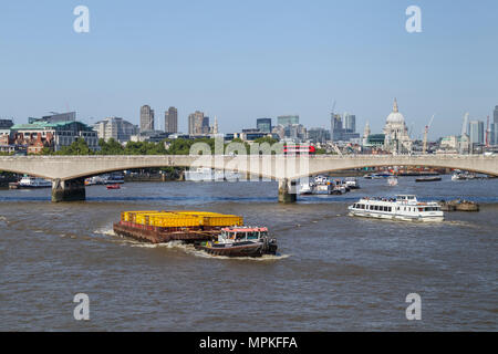 Cory Riverside tug 'Redoubt' il traino di una chiatta caricato con il giallo dei contenitori lungo il fiume Tamigi sopra il ponte di Waterloo, London, Regno Unito Foto Stock