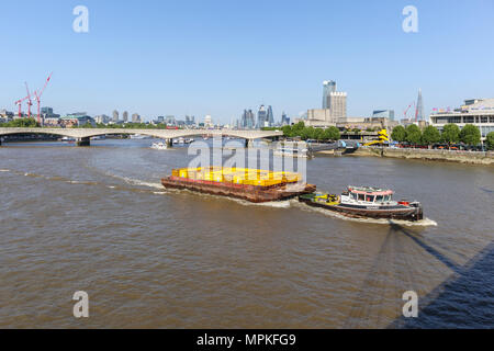 Cory Riverside tug 'Redoubt' il traino di una chiatta caricato con il giallo dei contenitori lungo il fiume Tamigi sopra il ponte di Waterloo, London, Regno Unito Foto Stock