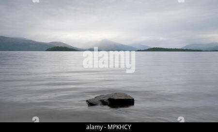 Moody loch lago atmosferica nuvole grigio scuro acqua Lomond Scozia highlands scena di paesaggio all'aperto Foto Stock