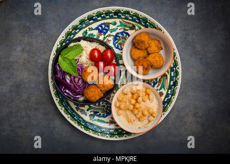 Il cous cous patata dolce falafel ciotola con cavolo rosso, pomodoro, menta e hummus Foto Stock