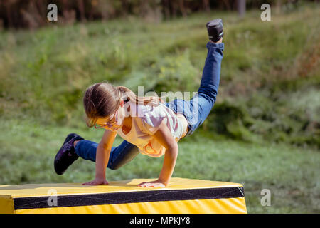 Ragazza bambino la pratica (pratica) Parkour ginnastica fuori sul cavallo di Vaulting Foto Stock