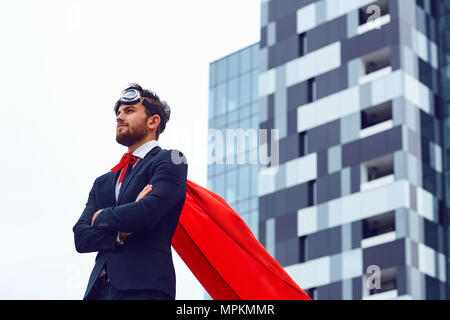 Un imprenditore in un costume da supereroe si erge contro un business b Foto Stock