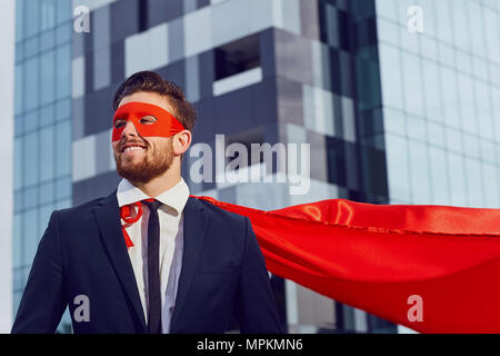 Un imprenditore in un costume da supereroe si erge contro un business b Foto Stock