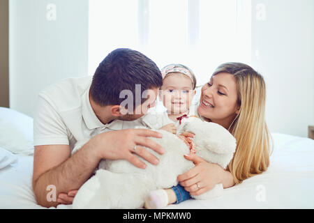 La famiglia felice sdraiato sul letto in camera da letto Foto Stock