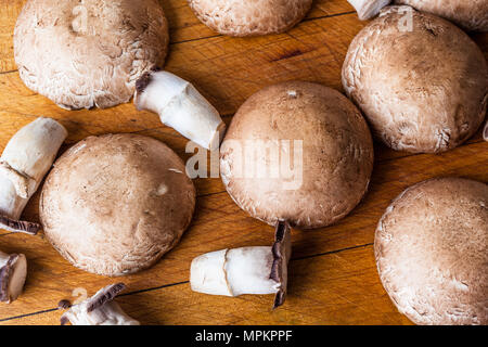 Funghi champignon caps e piccioli sul tagliere di legno dal di sopra Foto Stock
