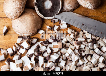 Tagliare marrone di funghi champignon sul tagliere di legno con un coltello da sopra Foto Stock