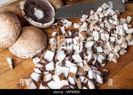 Tagliare marrone di funghi champignon sul tagliere di legno con il coltello dalla parte laterale Foto Stock