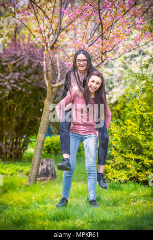 Due graziose sorelle ragazze abbracci e divertirsi insieme, indossando vestiti alla moda, emozioni positive. Foto Stock