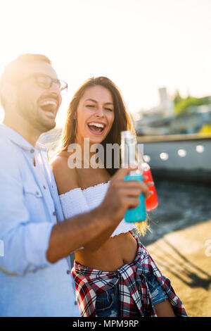 Felice coppia giovane bevendo un cocktail sulla terrazza sul tetto Foto Stock