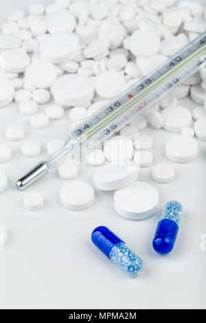 Grappolo di compresse di colore bianco con blu pillole e termometro. Sparse in pillole.messa a fuoco selettiva. Foto Stock