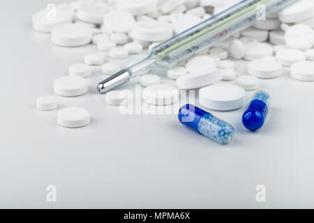 Grappolo di compresse di colore bianco con blu pillole e termometro. Sparse in pillole.messa a fuoco selettiva. Foto Stock