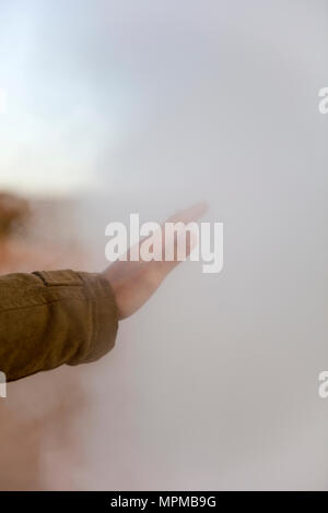 La mano del giovane toccando il vapore a geyser Sol de Manana a Eduardo Avaroa fauna Andina riserva nazionale in Bolivia Foto Stock