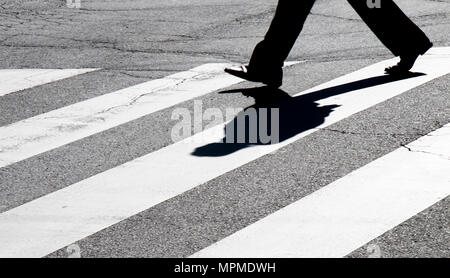 Città sfocate street zebra incrocio con uno a piedi gambe pedonale silhouette facendo ombra in bianco e nero a contrasto elevato Foto Stock