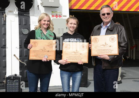 Julie, Eliza e Douglas Sheehan, discendenti di Coast Guard hero segnalatore 1. Classe Douglas Munro, tenere listone onorario proprietario delle placche e monete unità donati al loro dal Capitano ed equipaggio del guardacoste Munro a Seattle, 31 marzo 2017. Plank proprietario è un termine nautico che indica chi è stato attivamente impegnato nella costruzione di una nave e servita nell'unità una volta che il recipiente è stato commissionato e messo in servizio. Stati Uniti Coast Guard foto di Sottufficiali di seconda classe Jonathan Klingenberg. Foto Stock