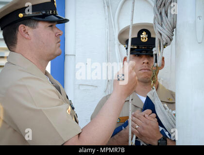 SAN DIEGO (Mar. 31, 2017) Capo di Boatswain Mate Jose Salas, da El Monte, CA. e capo di Boatswain Mate Nicholas beccaccini, da Ocala, Fl., assegnato alla spiaggia di unità master uno (BMU-1), sollevare il ensign nazionale in onore del Chief Petty Officer (CPO) 124compleanno. Il rango di chief petty officer è stato istituito il 1 aprile 1893. (U.S. Navy foto di Lt. Devin Arneson/RILASCIATO) Foto Stock