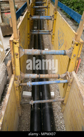 In plastica isolate di tubi per teleriscaldamento giacente su supporti di plastica e ghiaia in trincea nella Goethestrasse. Foto Stock