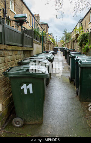 Righe di verde wheelie linea di scomparti di viuzze tra case terrazza in Saltaire, Yorkshire. Foto Stock