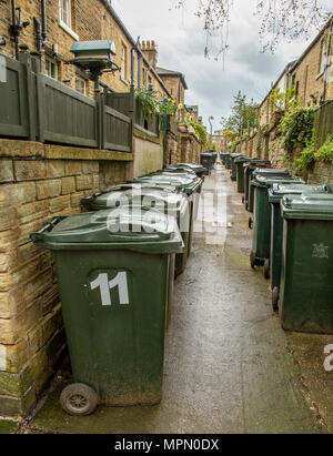 Righe di verde wheelie linea di scomparti di viuzze tra case terrazza in Saltaire, Yorkshire. Foto Stock