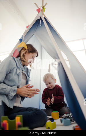 Madre giocando con suo figlio in una tenda a casa Foto Stock