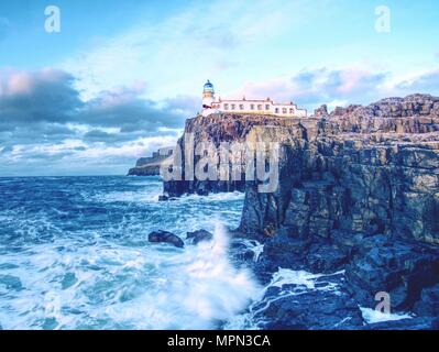 Famosa vista di Neist Point lighthouse sulla fine del mondo. Serata spumeggiante mare blu urta contro il forte cliff. L'Isola di Skye in Scozia Foto Stock