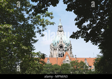 Torre del nuovo municipio in Hannover Germania incorniciata dagli alberi Foto Stock